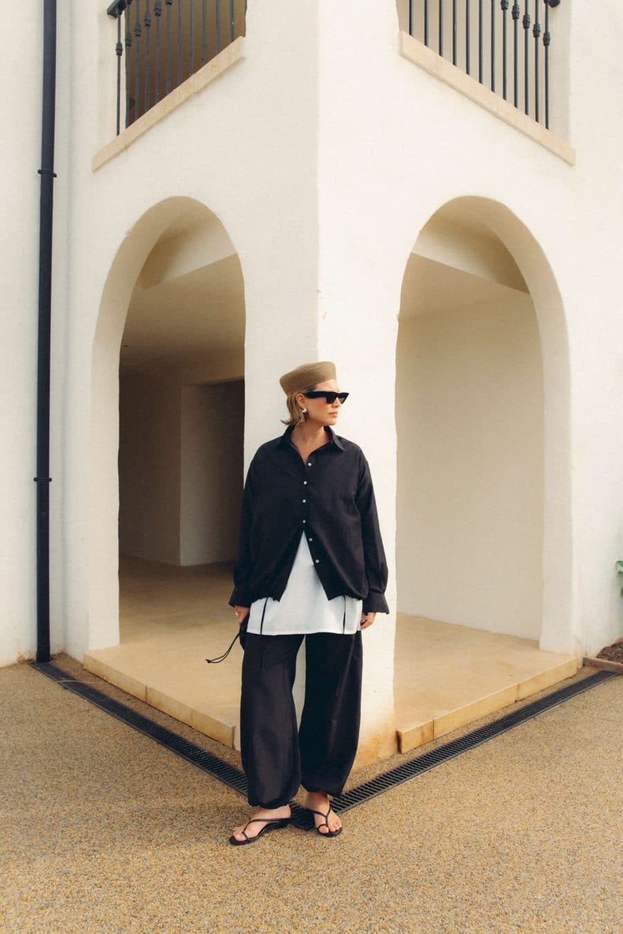 Woman in Asceno navy separates beneath white arches