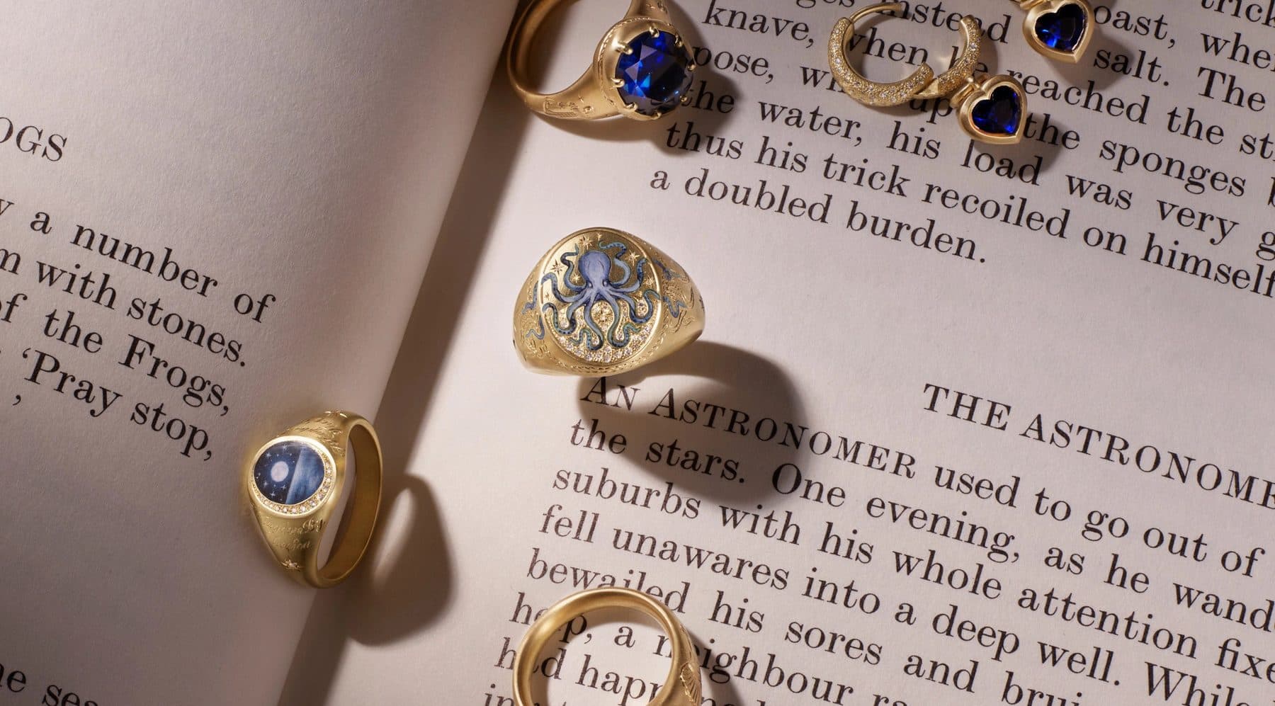 Cece gold signet and sapphire rings resting on the pages of an open book