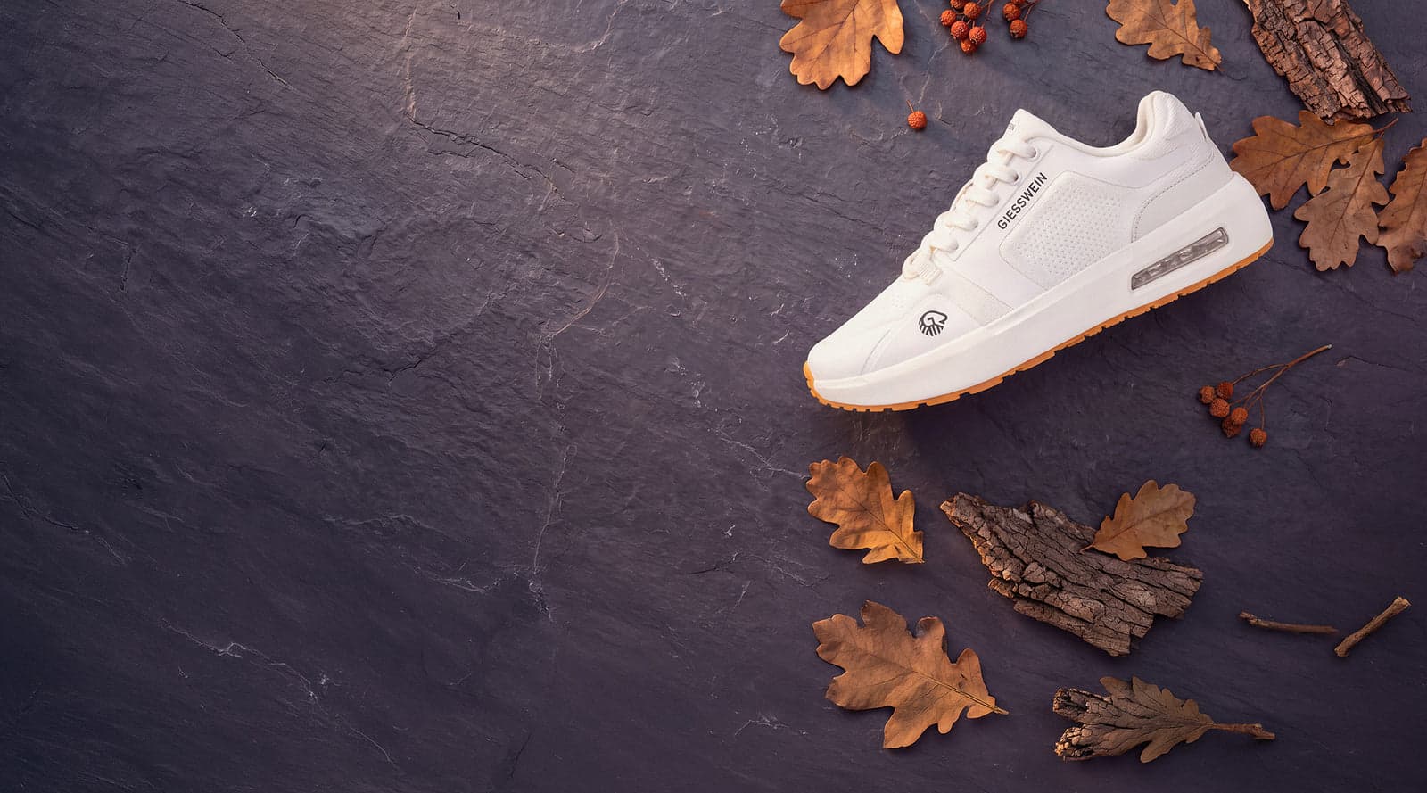 White Giesswein wool sneaker on slate with autumn leaves